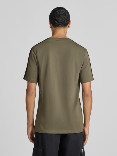 Männermodel trägt Regular Fit T-Shirt aus reiner Baumwolle Modell 'M 3S SJ LC T' von adidas, olivgrün mit schwarzen Details, Herren T-Shirt von adidas Sportswear, Ganzkörperansicht Rückansicht.