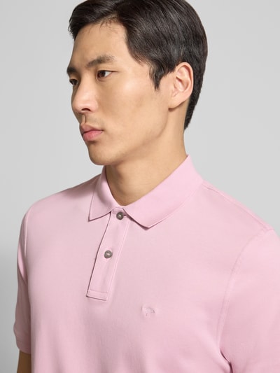 Männermodel trägt Regular Fit Poloshirt mit Logo-Stitching von Fynch-Hatton in Rosa, feine Baumwollstruktur, Nahaufnahme Oberkörper.