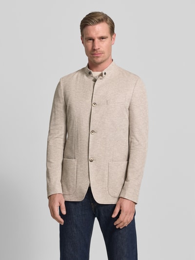 Męski model nosi Slim Fit Sakko mit Stehkragen von Roy Robson z mieszanki bawełny, nakładane kieszenie, listwa guzikowa, krój slim fit, długość tyłu w rozmiarze 50: 76 cm, szerokość ramion w rozmiarze 50: 44 cm, długość rękawów w rozmiarze 50: 68 cm, kolor jasny beż, faktura gładka; Ganzkörperansicht von vorne.
