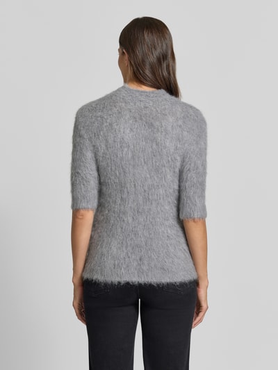 Frauenmodel trägt Strickshirt aus Alpaka-Mix mit kurzem Stehkragen von someday, grauer Farbton, körpernaher Schnitt, 1/2-Arm, Rückenlänge 60 cm, Ärmellänge 44 cm, weiche, leicht flauschige Textur, Ganzkörperansicht Rückansicht.