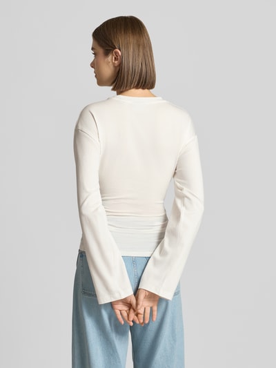 Kobiece model nosi bluzkę z długim rękawem z mieszanki bawełny, krój taliowany, okrągły dekolt, Model 'Paloma' od JJXX, długość tyłu w rozmiarze S: 57 cm, jasny kolor, gładka faktura, widok całej sylwetki z tyłu.