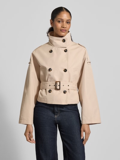 Frauenmodel trägt Kurze Trenchjacke mit Taillengürtel von Jake*s Collection in Beige, Baumwoll-Mix, Gerade Passform, Nahaufnahme Oberkörper. Rückenlänge 53 cm, Schulterbreite 48 cm, Brustweite 32 cm, Ärmellänge 52 cm, hoher Stehkragen, doppelreihige Knopfleiste, Schulterriegel.