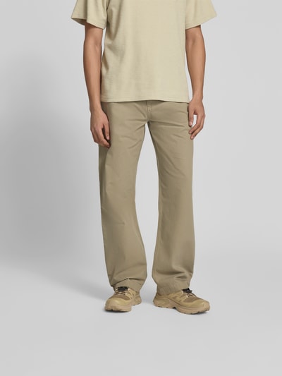 Männermodel trägt Straight Fit Jeans mit Gesäßtaschen von Forét aus Reine Baumwolle in Beige, Eingrifftaschen, Knopf-Reißverschluss, Ganzkörperansicht von vorne.