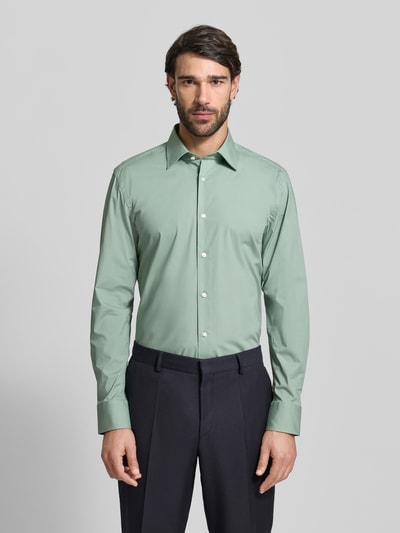 Męski model nosi Slim Fit Businesshemd aus Baumwoll-Mix Modell 'H-HANK-KENT' od BOSS, gładka zieleń, krój slim fit, easy iron, widok całej sylwetki z przodu.