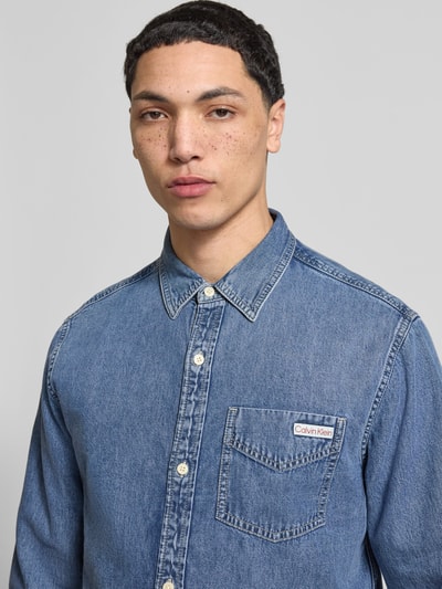 Männermodel trägt Regular Fit Jeanshemd mit Brusttasche und Label-Detail von Calvin Klein Jeans, reine Baumwolle, Nahaufnahme Oberkörper.