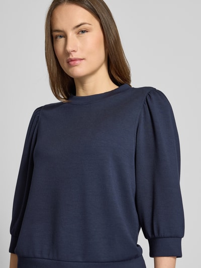 Modelka damska ma na sobie Loose Fit Sweatshirt mit 3/4-Arm od Rich & Royal, kolor granatowy, balonowe rękawy, stójka, zbliżenie na górną część ciała.