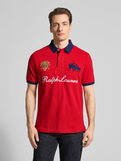Männermodel trägt Regular Fit Poloshirt aus reiner Baumwolle von Polo Ralph Lauren in Rot, unifarben mit Logo-Stitching, Ganzkörperansicht von vorne.