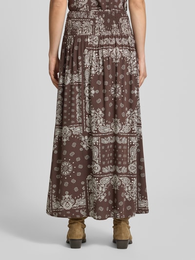 Vrouwenmodel draagt bruine uitgespreide maxi rok van pure viscose model 'SAKI AMBEL' van Only met wit paisley motief, dames maxi-rok, ganzonderaanzicht achteraan.
