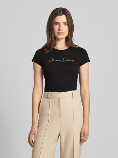 Frauenmodel trägt T-Shirt mit Logo und Rundhalsausschnitt von ARMANI EXCHANGE aus reiner Baumwolle, Slim Fit, Schwarz, Schriftzug vorn, Ganzkörperansicht von vorne
