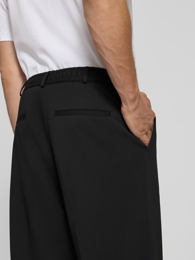 Mężczyzna nosi spodnie materiałowe Straight Fit Stoffhose mit Viskose-Anteil Modell 'Glen' od Zuitable, czarny, mieszanka materiałów z dodatkiem wiskozy, kieszenie z tyłu i wpuszczane, szerokość w rozmiarze 50: 45 cm, długość wewnętrzna nogawki: 71 cm, widok z tyłu, detal boczny.