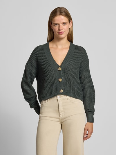 Vrouwenmodel draagt boxy fit gebreid jack met v-hals model 'CAROL' van ONLY in donkergroen, dames, grofgebreide textuur, vooraanzicht, Ganzkörperansicht von vorne.