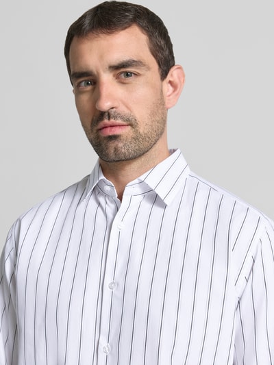 Männermodel trägt Loose Fit Freizeithemd mit Kentkragen Modell 'Miles' von JOOP!, weiß mit schwarzen Streifen, Nahaufnahme Oberkörper, Baumwollmaterial, Kontext: Herren Freizeithemd, Allover-Look, Größe M Rückenlänge 72 cm, Schulterbreite 42 cm, Ärmellänge 64 cm.