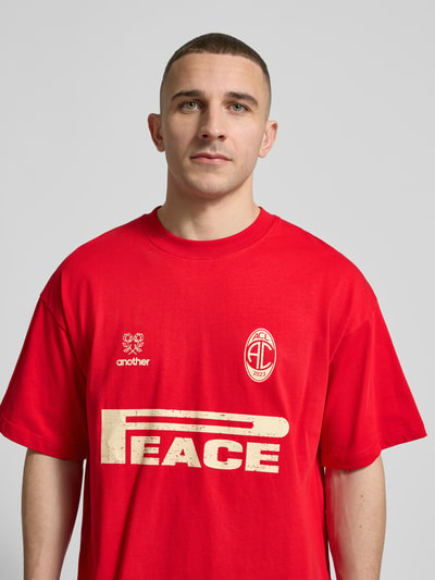 Männermodel trägt Regular Fit T-Shirt mit Logo-Print von ANOTHER COTTON LAB in Rot, reine Baumwolle, Nahaufnahme Oberkörper.