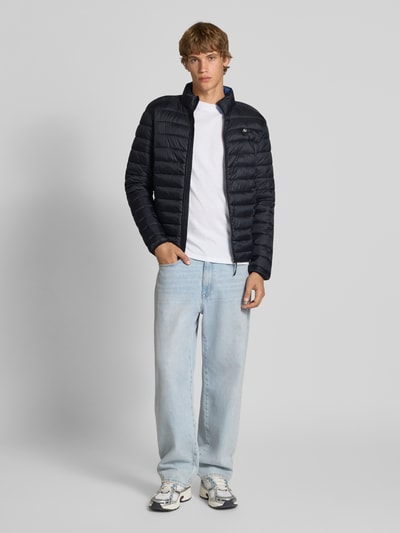 Mannelijk model draagt Steppjacke met opstaande kraag model 'Romsey' van Blend in recht fit, zwart met lichte structuur, frontale volledige lichaamsweergave.