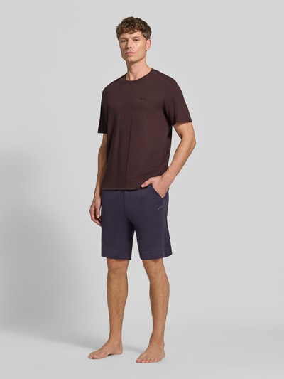 Männermodel trägt Regular Fit T-Shirt aus Baumwoll-Mix Modell 'WAFFLE' von BOSS in Dunkelbraun, kombiniert mit kurzen Hosen, Ganzkörperansicht von vorne. Herren T-Shirt von BOSS.