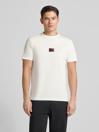 Männermodel trägt Regular Fit T-Shirt aus reiner Baumwolle Modell 'DANOTIE' von HUGO in Weiß mit Label Print, Ganzkörperansicht von vorne.