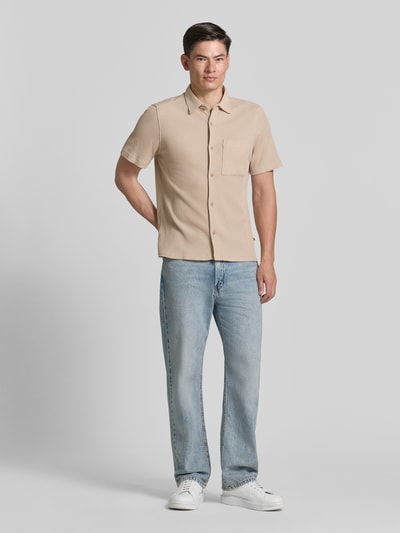 Männermodel trägt Regular Fit Freizeithemd aus Baumwoll-Mix von s.Oliver RED LABEL in Beige, Waffelstruktur, kurzarm, unifarben, Ganzkörperansicht von vorne.