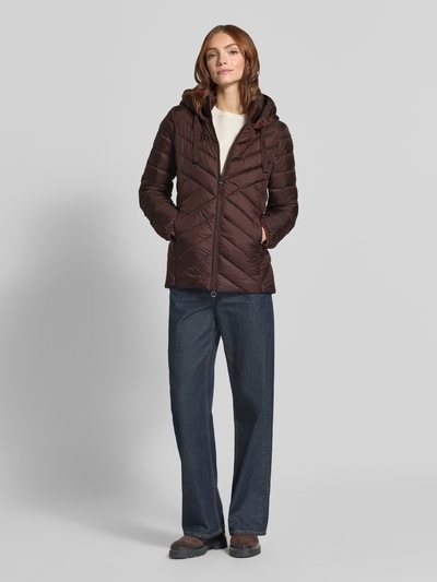 Vrouwenmodel draagt Slim Fit gewatteerd jack met tweewegritssluiting van s.Oliver RED LABEL, bruin met stikseldetail, volledig silhouet vooraan.