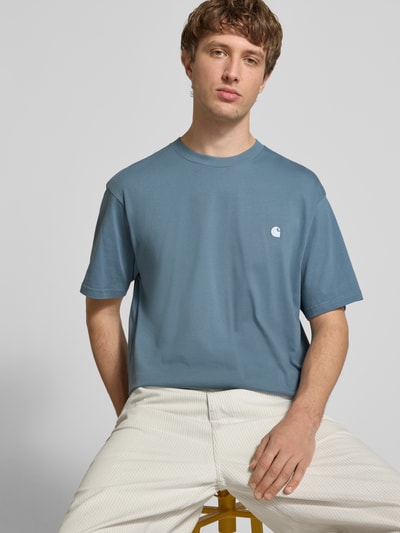 Männermodel trägt Herren T-Shirt mit Label-Stitching Modell 'Madison' von Carhartt Work In Progress, Reine Baumwolle, Regular-Fit, Rundhalsausschnitt, Rückenlänge bei Größe M: 75 cm, dezente Blau-Weiß-Kombination, glatte Oberfläche, Nahaufnahme Oberkörper.