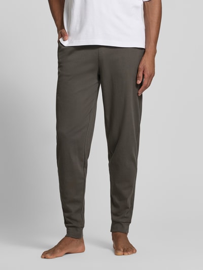 Mężczyzna nosi Lounge-Hose mit elastischem Bund und Eingrifftaschen von Christian Berg Men, bawełna, krój regular fit, dł. wewnętrzna nogawki 40 cm w rozmiarze M, wpuszczane kieszenie, kolor ciemny, całkowity widok z przodu.