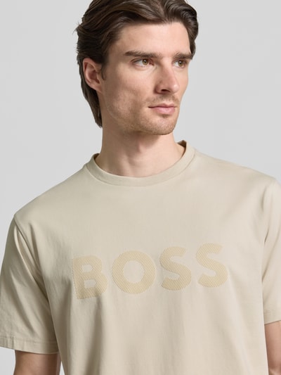 Männermodel trägt Regular Fit T-Shirt aus Baumwoll-Mix Modell 'ICONIC' von BOSS Green in Beige mit Rundhals, Nahaufnahme Oberkörper.