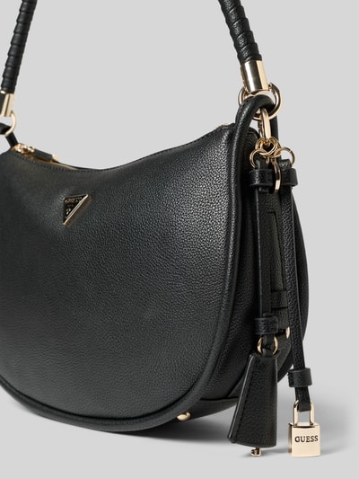 Produktfoto, schwarze Handtasche mit Label-Applikation von Guess, strukturierte Lederoptik, goldene Details, Anhänger, Nahaufnahme, Hauptfach mit Reißverschluss, Tragehenkel, Maße 30x19x9 cm, Schulterriemen 53 cm.