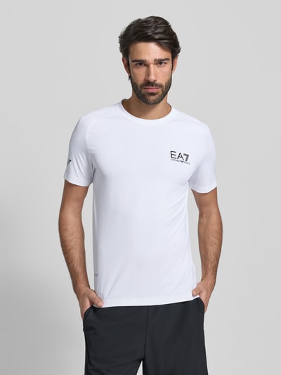 Męski model nosi T-shirt mit Label-Print od Armani, biały, mieszanka materiałów z dodatkiem streczu, krój slim fit, okrągły dekolt, długość tyłu 69 cm w rozmiarze M, Ganzkörperansicht von vorne.