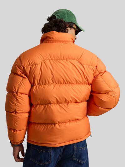 Männermodel trägt Steppjacke mit Zweiwege-Reißverschluss von POLO RALPH LAUREN in Orange aus Polyester, unifarben, Ganzkörperansicht Rückansicht.