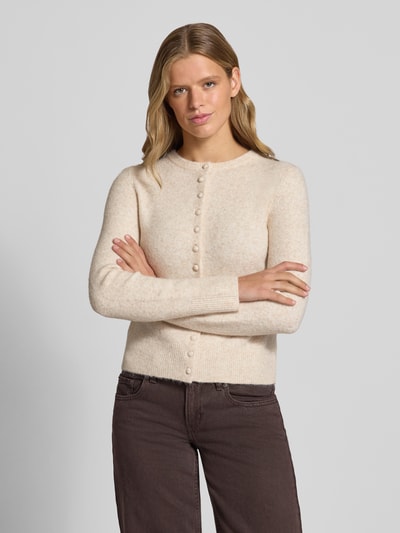 Modelka nosi Slim Fit Strickjacke mit Woll-Anteil Modell 'Sia' od Topshop, kremowy kolor, krój slim fit, dzianinowa faktura, długie rękawy, prążkowane wykończenia, pełna listwa guzikowa, materiał elastyczny z domieszką wełny, długość tyłu w rozmiarze S: 50 cm, długość rękawa w rozmiarze S: 64 cm, widok z przodu na górną część ciała.
