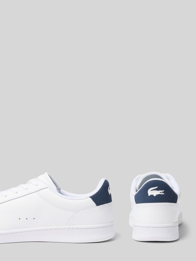 Produktfoto, Sneaker aus echtem Leder Modell von Lacoste in Weiß mit dunkelblauen Details, klare Linien, glatte Oberfläche.