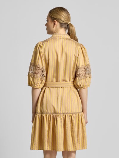 Frauenmodel trägt Knielanges Kleid mit Spitze und Gürtel Modell 'CATLEYA' von SUNCOO PARIS, gelb gestreift, tailliert, Rückansicht