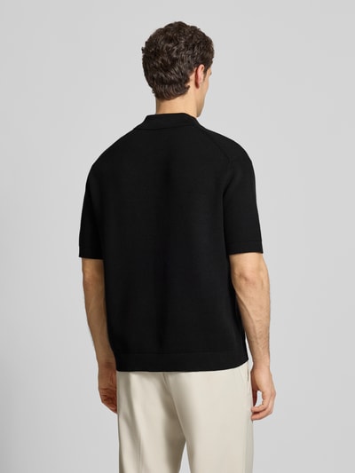 Männermodel trägt Relaxed Fit Poloshirt aus reiner Baumwolle Modell 'DANE' von SELECTED HOMME in Schwarz, Strickoptik, Ganzkörperansicht Rückansicht