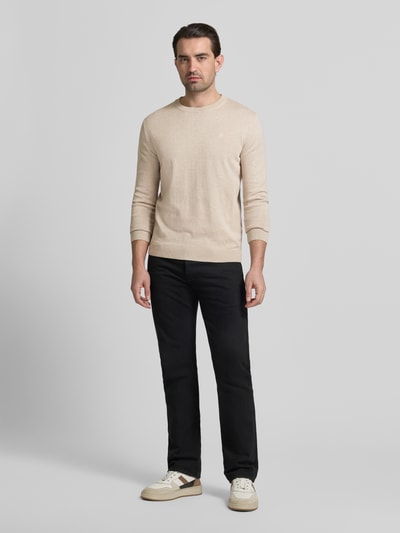 Männermodel trägt Regular Fit Strickpullover aus reiner Baumwolle von Tom Tailor in Beige, unifarben, Logo-Detail, Ganzkörperansicht von vorne.