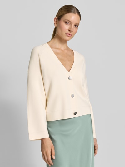 Frauenmodel trägt Strickjacke aus Viskose-Mix mit V-Ausschnitt von comma, cremefarben, lockerer Schnitt, Nahaufnahme Oberkörper.
