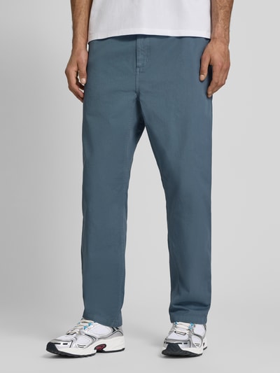 Männermodel trägt blaue Hose mit elastischem Bund Modell 'Moraga' von Carhartt Work In Progress aus Reine Baumwolle, Regular-Fit, Ganzkörperansicht von vorne.