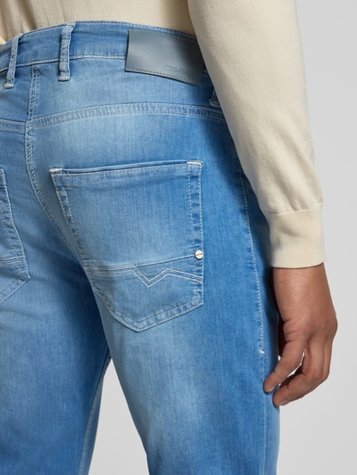 Männermodel trägt Regular Fit Jeans aus Baumwoll-Mix von MAC in Hellblau, 5-Pocket-Design, Label-Patch, Kontrastnähte, Nahaufnahme Rückansicht.