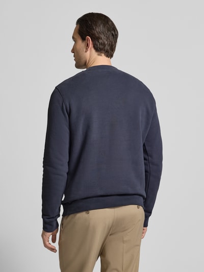 Männermodel trägt Regular Fit Sweatshirt aus reine bio katoen Modell 'BAARO FLEECE' van Armedangels, effen donkerblauw, geribde boorden, logo detail, ronde hals, lange mouwen, sweatstof, rugaanzicht, ganzkörperansicht rückansicht.