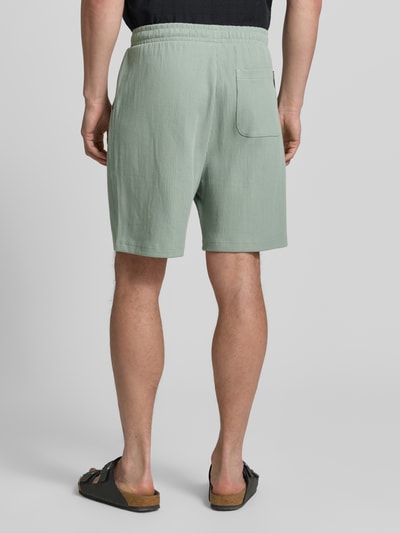 Männermodel trägt Relaxed Fit Sweatshorts aus reiner Baumwolle von Tom Tailor Denim in Optik: Unifarben, Rippstrick, Ganzkörperansicht Rückansicht.