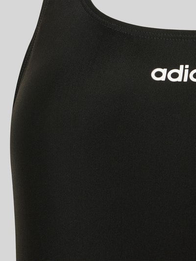 Frauenmodel trägt Badeanzug mit Label Print von adidas Sportswear, Optik: Unifarben, Logo-Print, Nahaufnahme Oberkörper.