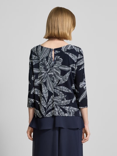 Frauenmodel trägt Blusenshirt mit rückseitigem Schlüsselloch-Ausschnitt von Vera Mont im Material-Mix mit Stretch-Anteil, dunkle Töne, florales Muster, gerader Schnitt, 3/4-Arm, fließende Textur, Rückenlänge bei Größe 36: 57 cm, Ganzkörperansicht Rückansicht.