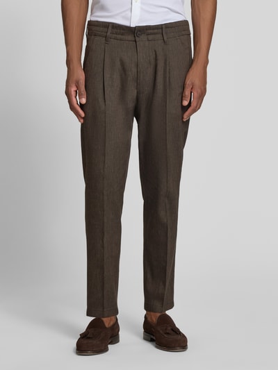 Männermodel trägt Hose mit Bügelfalte und elastischem Bund Modell 'CHASY' von Drykorn, brauner Leinen-Mix mit Viskose-Anteil, Slim-Fit, Knopf- und Reißverschluss, französische Eingrifftaschen, klassische Gesäßtaschen, glatte Textur, Bundweite 44 cm, Innenbeinlänge 66 cm, Ganzkörperansicht von vorne.