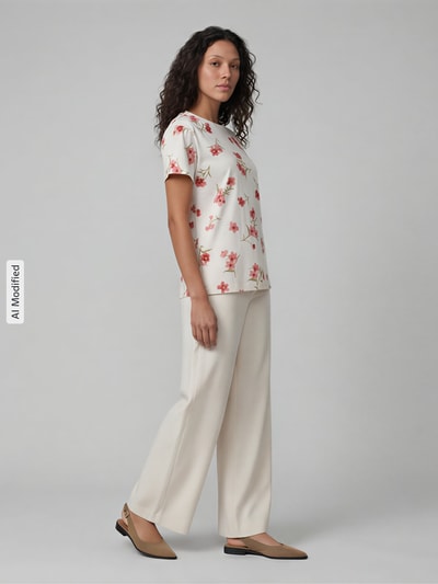 Frauenmodel trägt T-Shirt im Allover-Look mit Rundhalsausschnitt von Jake*s Casual, cremefarben mit floralen Mustern, Regular Fit, reine Baumwolle, kombiniert mit hellen Stoffhosen, seitliche Ganzkörperansicht.