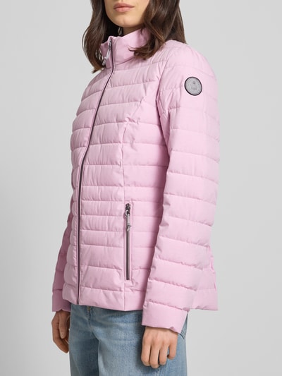Modelka nosi kurtkę pikowaną z zamkiem błyskawicznym i kieszeniami, różowa, model 'GS 111' od G.I.G.A. DX, krój slim fit, stójka, długość tyłu w rozmiarze 36: 67 cm, szerokość ramion w rozmiarze 36: 38 cm, szerokość klatki piersiowej w rozmiarze 36: 49 cm, długość rękawów w rozmiarze 36: 65 cm, widok z przodu w ujęciu prawie całopostaciowym.