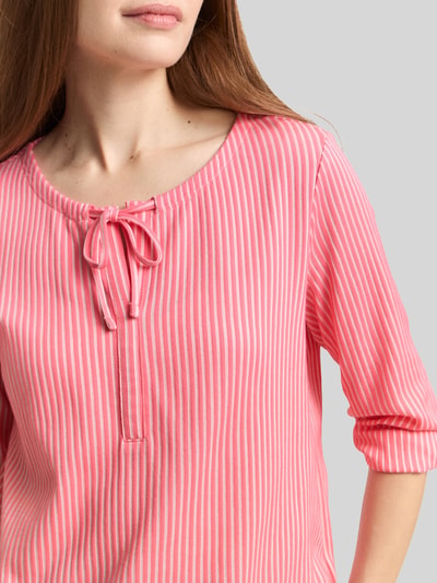 Frauenmodel trägt Regular Fit T-Shirt aus Baumwoll-Mix von Tom Tailor, rosa-weiß gestreift mit V-Ausschnitt, Feinrippstruktur, Nahaufnahme Oberkörper.
