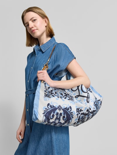 Frauenmodel trägt Handtasche mit Tragehenkel Modell 'FOULARD' von Liu Jo White aus Satin mit blauem Ornamentmuster, Nahaufnahme Oberkörper.