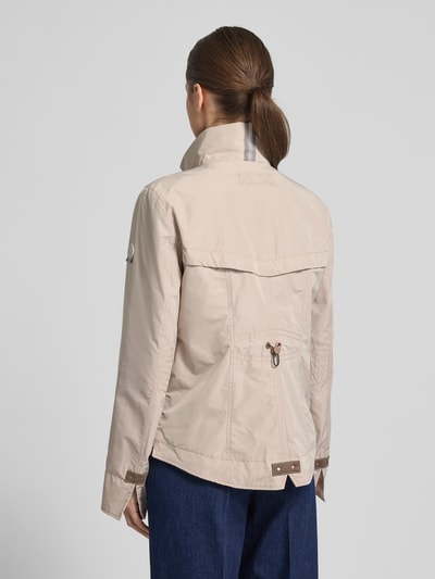 Frauenmodel trägt Regular Fit Jacke mit Logo-Patch von Gil Bret in Beige, Stehkragen mit Tunnelzug, Reißverschlusstaschen, Ganzkörperansicht Rückansicht.
