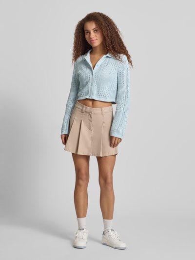 Vrouwenmodel draagt Regular fit cardigan met polokraag model 'Sue' van JJXX, puur katoen, langemouwen, ajourtricotlook, knoopsluiting, elastische mouwboorden, ruglengte maat S 43 cm, mouwlengte maat S 63 cm, lichtblauw, rechte vormen, zachte textuur. Vooraanzicht volledig lichaam.