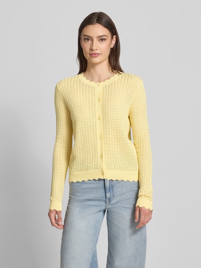 Frauenmodel trägt Regular Fit Strickjacke aus reiner Baumwolle Modell 'SCOUT' von Pieces, Optik: Unifarben, Semitransparente-Optik, Rundhals, Langarm, Knopfleiste, Strick-Struktur in Gelb, Gerippt an Ärmelabschluss und Rumpfabschluss, Materialverarbeitung: Strick, Ganzkörperansicht von vorne.