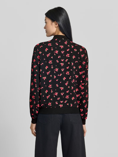 Frauenmodel trägt Regular Fit Blouson mit Allover-Muster Modell 'COCO' von VERO MODA mit schwarzem Grund und roten Blüten, Ganzkörperansicht Rückansicht.