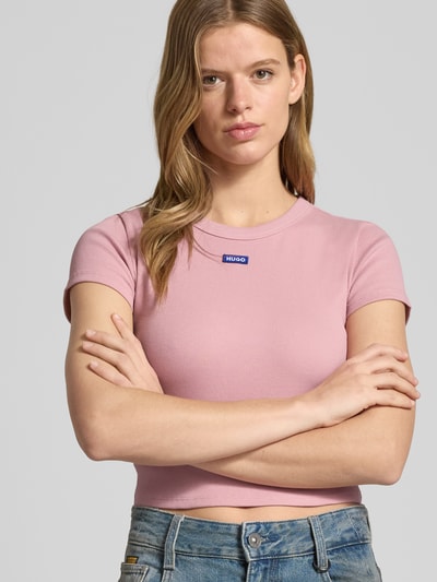 Kobiece modelka nosi Slim Fit T-Shirt aus Baumwoll-Mix Modell 'BABY TEE_B' od Hugo Blue, jednokolorowy róż, prążkowana faktura, okrągły dekolt, krótki rękaw, mieszanka bawełny, efekt: jednolity kolor, Ganzkörperansicht z przodu.